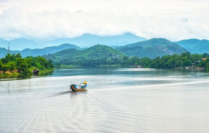 boat on calm river with green mountains