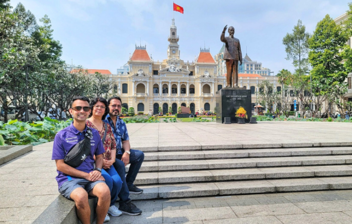 a group of tourists in front of the statue of Ho Chi Minh